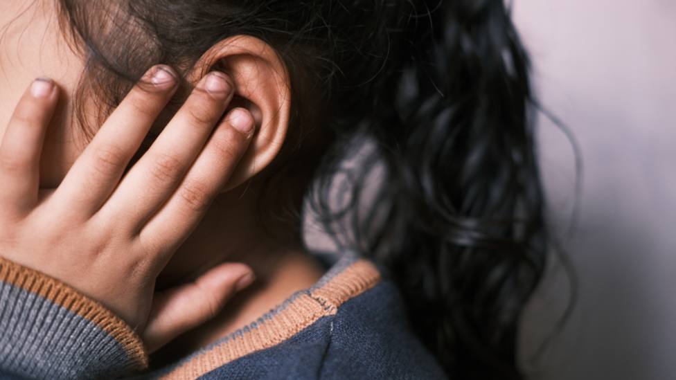 Una niña protege sus oídos